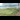 Railway Pioneers: A photo from the window of a train, looking out to see it curving around a bend, with a lush, green field to the left.